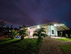 Una casa moderna con un porche cubierto, rodeada de vegetación.