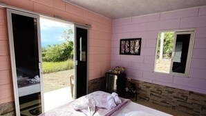 A room with a bed, a sliding door to a balcony, a small table, and a picture on the wall. - Macori Cabañas Campestres (Rivera)