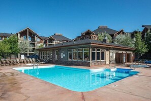 A pool area with a building that has large windows and a stone facade. - Laguna | Lake | Outdoor Pool/Hot Tub | Gym | Pets (Invermere)