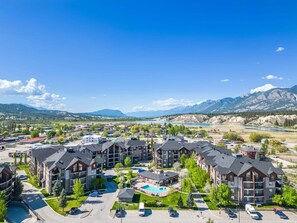 A multi-story hotel with a pool, surrounded by greenery and mountains. - Laguna | Lake | Outdoor Pool/Hot Tub | Gym | Pets (Invermere)