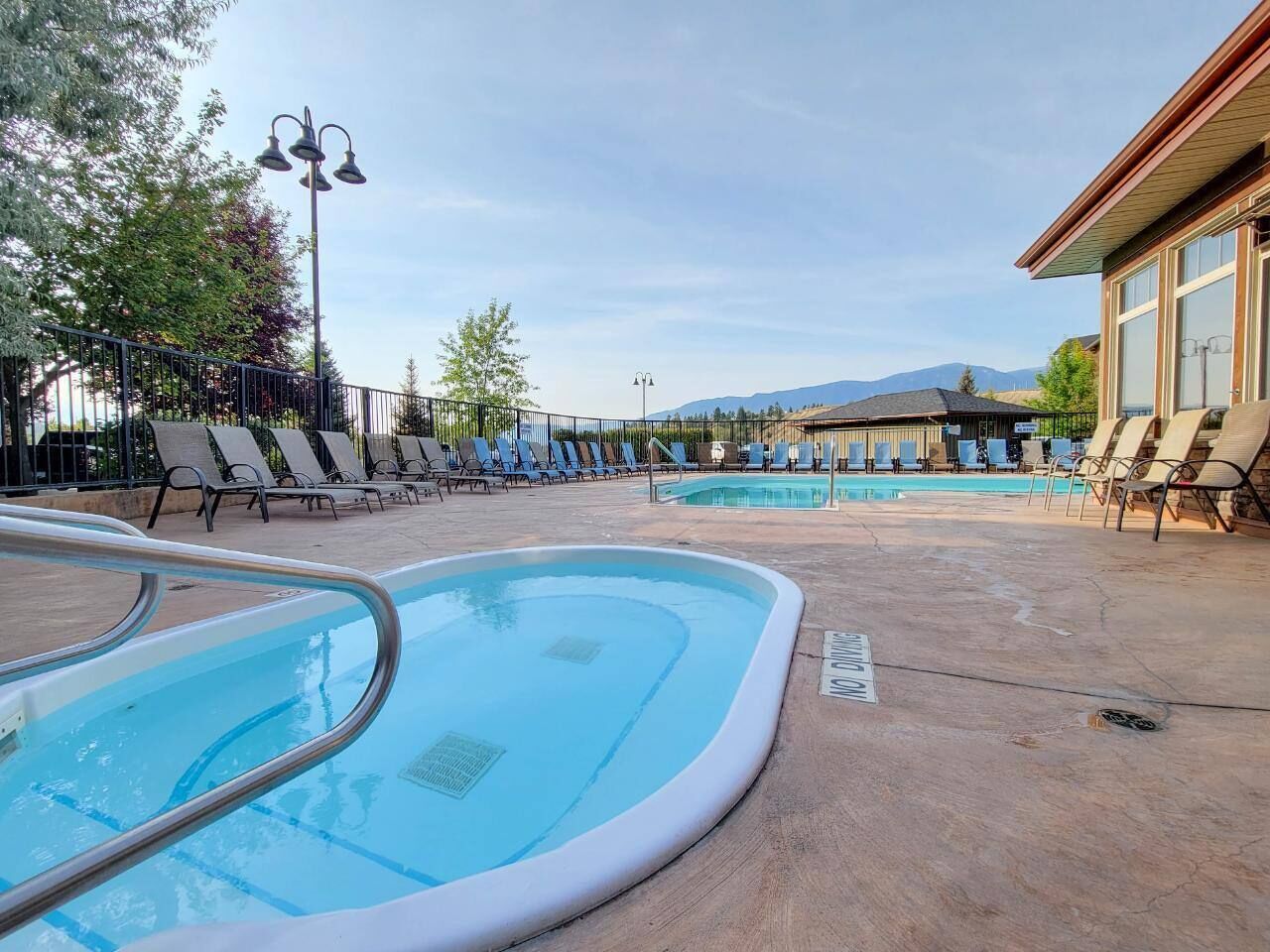 Un espace piscine avec des chaises longues et un bâtiment en arrière-plan.