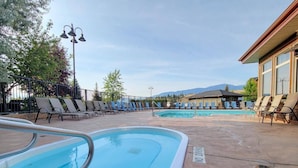 Zona de piscina con sillones de descanso y un edificio al fondo.