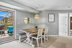 A dining area with a wooden table, white chairs, a hanging light fixture, a mirror, and a framed picture on the wall. - Laguna | Lake | Outdoor Pool/Hot Tub | Gym | Pets (Invermere)
