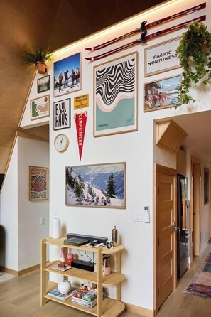 Ein Zimmer mit einem Holzbodenregal, gerahmten Bildern und einer Pflanze an der Wand.