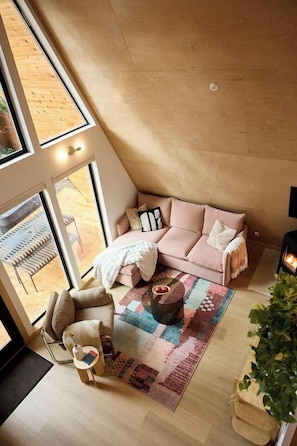 Ein Zimmer mit hohen Decken, einem großen Fenster, einem Sofa, einem Couchtisch und einem kleinen Beistelltisch.