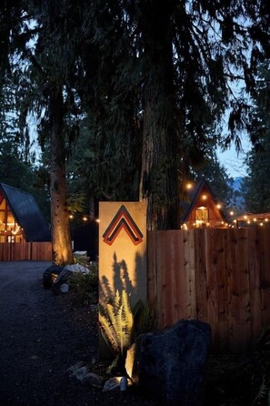 Ein Holzzaun mit einem Schild, eine Holzhütte und ein großer Baum.