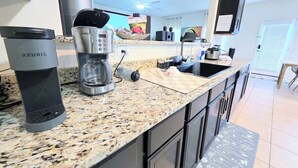 A modern kitchen with a Keurig coffee maker, a coffee pot, and a countertop. - Mid Century Manor,  4 bed/2.5 bth, 150" Projector, TVs all rooms, 3 King Beds! (Manor)