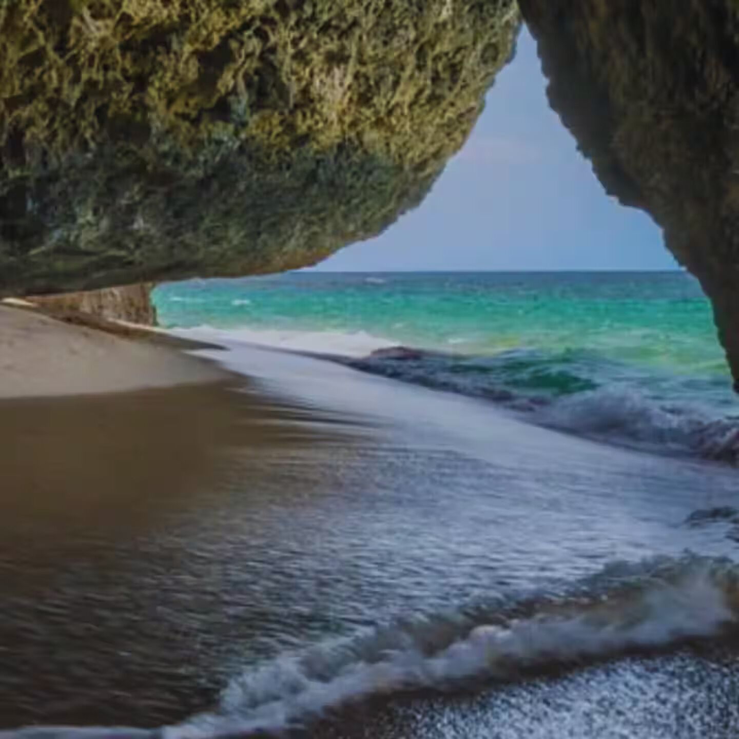 A beach with a rock formation creating a natural archway.