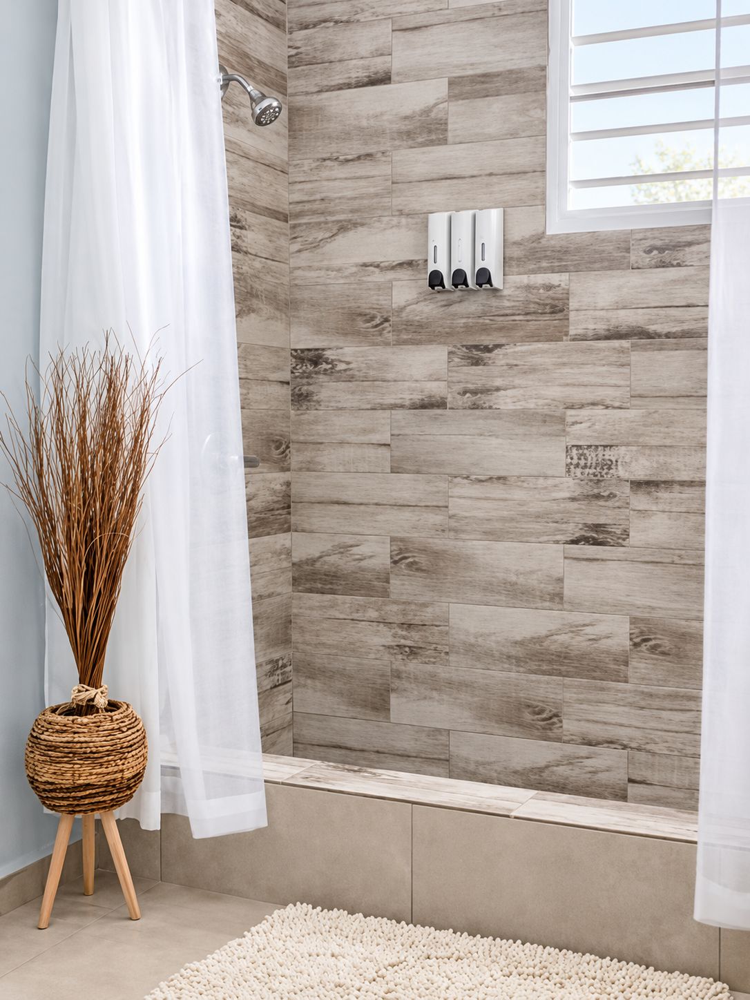 Ein Badezimmer mit Dusche, einem weißen Vorhang, einem Korbwäscheschrank und einer strukturierten Wand.