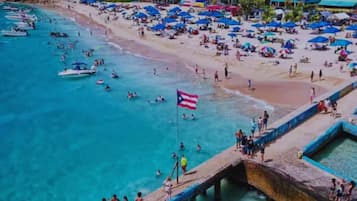 Una playa con muelle, agua turquesa cristalina y una bandera.