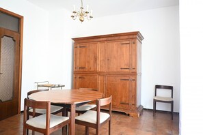 Un coin repas comprenant une table en bois, quatre chaises, un buffet et un lustre.