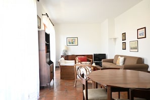 A living room with a dining table, sofas, a television, and a fireplace.