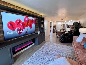 A modern living room with a flat-screen TV, a patterned rug, and a sofa. - Fire Fly Loft by Branson Landing-Waterfront (Branson)