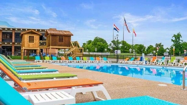 Un espace piscine avec des chaises longues et un bâtiment en bois doté de balcons.