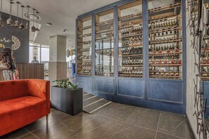 Un interno moderno con una grande esposizione di vini, un divano rosso e una pianta.