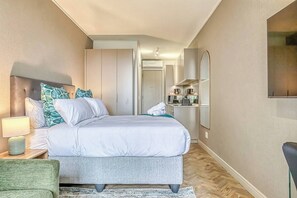 Ein Schlafzimmer mit Bett, Nachttisch, Lampe und einem grünen Sessel.