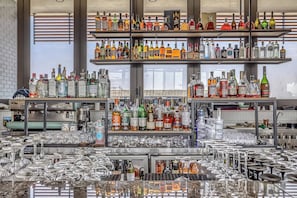 Un'area bar con scaffali pieni di bottiglie di liquore e numerosi bicchieri.