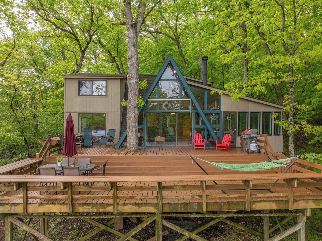 Una cabaña con terraza, asientos al aire libre y zona de barbacoa.