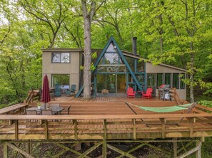 A cabin with a deck, outdoor seating, and a grill area.