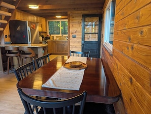 A wooden dining table with chairs, a mat, and a bowl in the center.