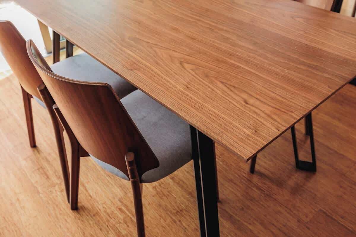 A wooden dining table with chairs, a grey cushion, and black metal legs.