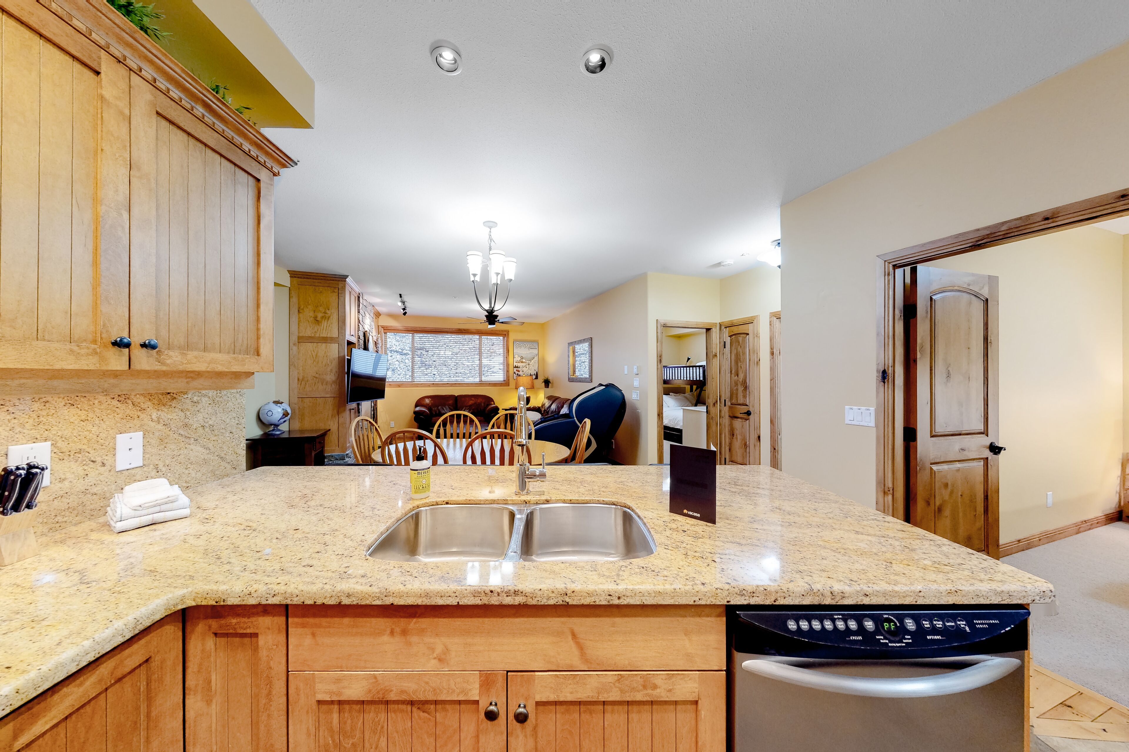 A kitchen with wooden cabinets, a granite countertop, a double sink, and a dishwasher.