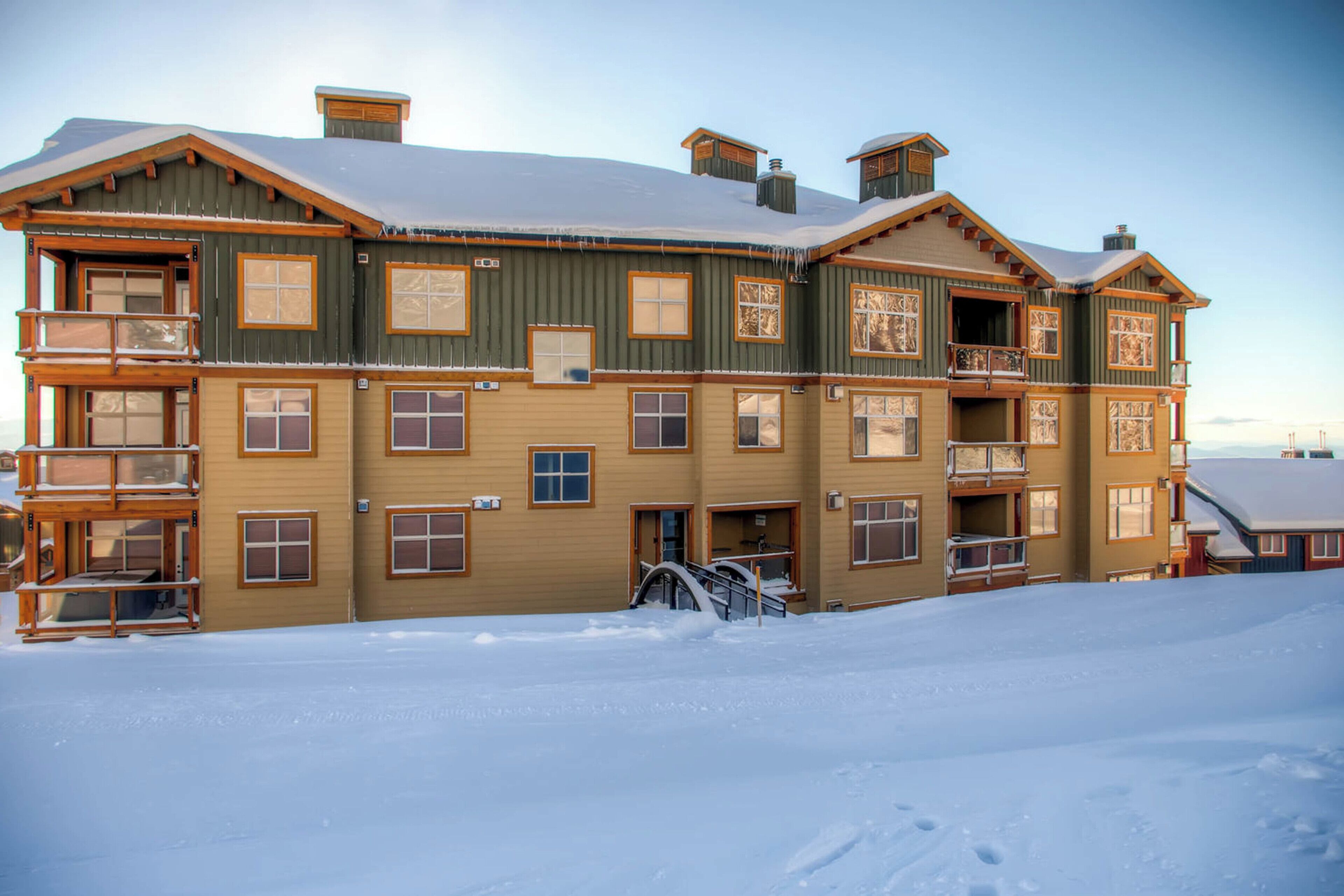 A multi-story building with a wooden facade and balconies, surrounded by snow.