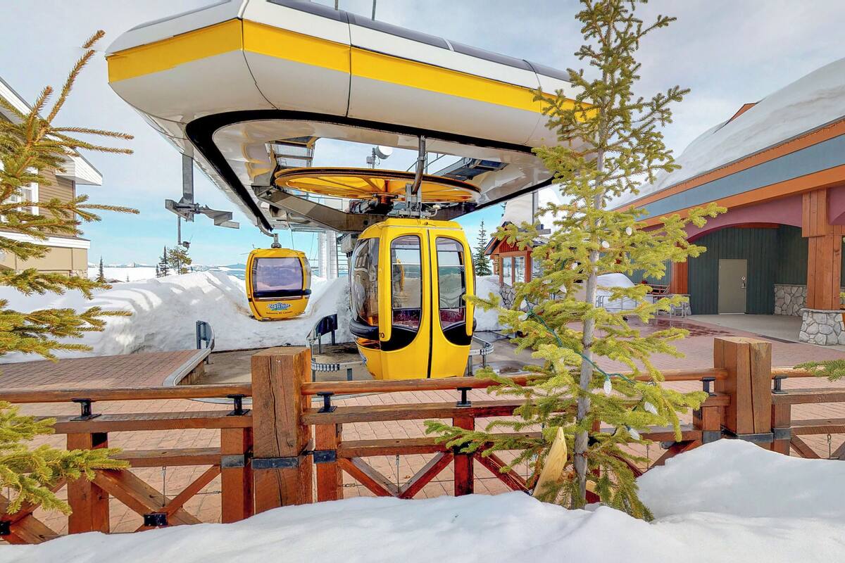 A yellow cable car at a station with a building in the background.