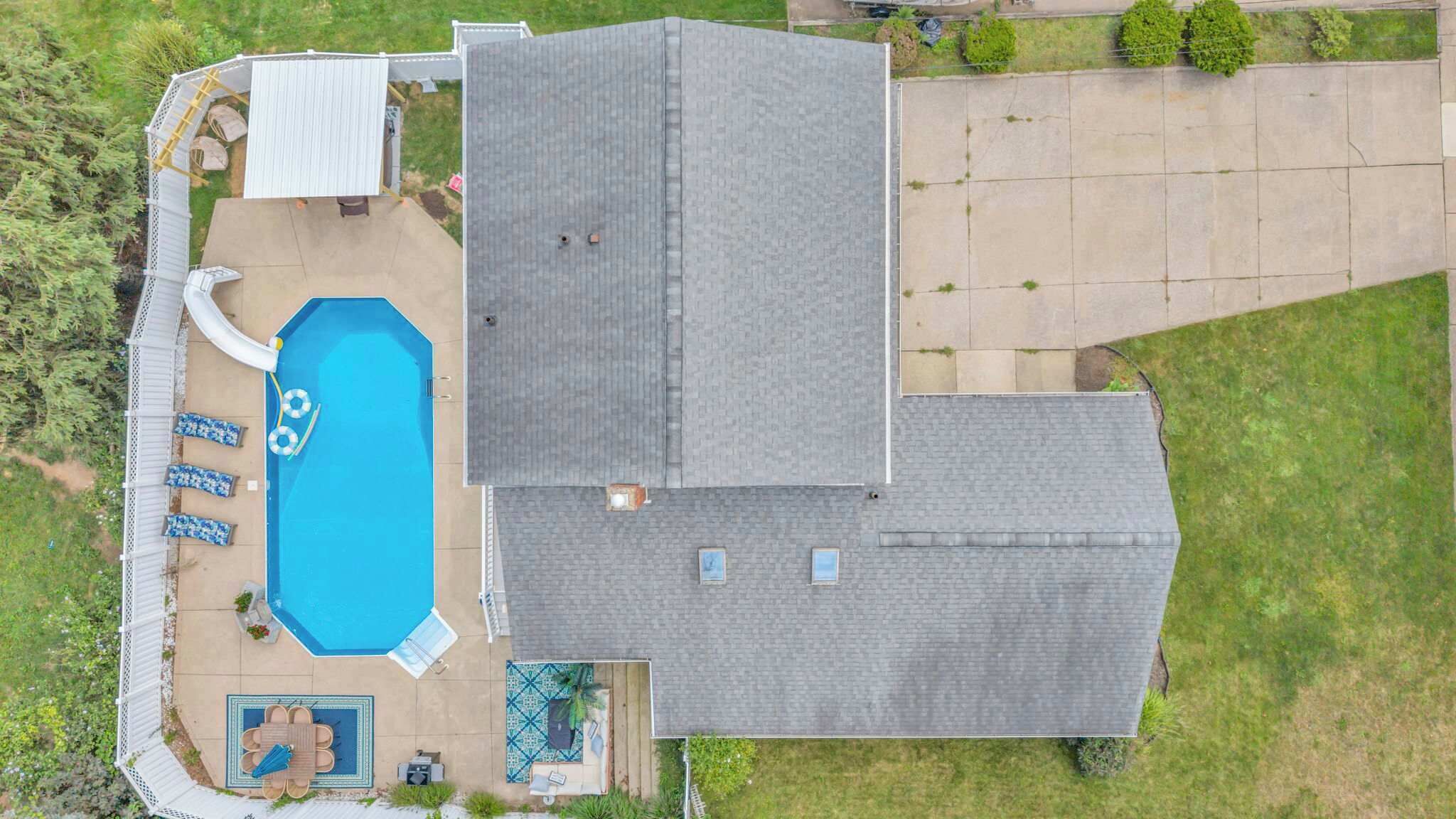 Um imóvel residencial com piscina, mobiliário de jardim e quintal cercado.
