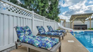 A poolside area with lounge chairs and a slide. - Backyard Pool - Hot Tub - Game Room (Akron)