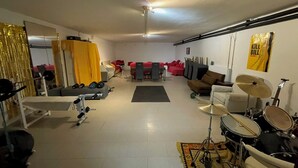A spacious living area with a sofa set, a dining table, and a drum set.