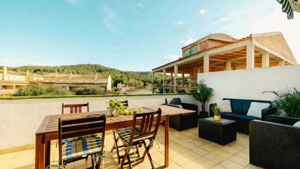 Eine Terrasse im Freien mit Tisch, Stühlen, einer Couch und einem Blumentopf.