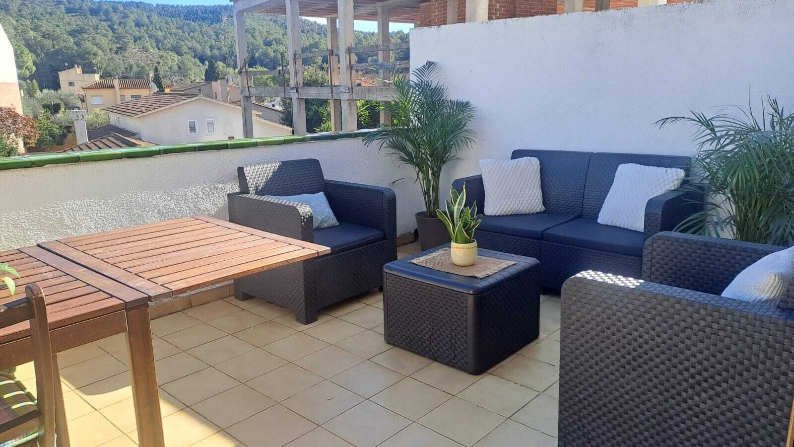 An outdoor patio with a wooden table, two sofas, and a small coffee table.