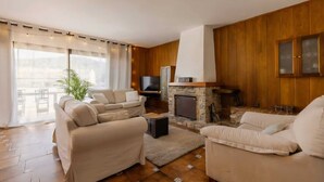 Ein Wohnzimmer mit Kamin, Sofas, einem Fernseher und einem Essbereich mit Tisch und Stühlen.