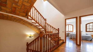 Eine Treppe mit Holzbalustern, einer Ziegelwand und einem Zimmer mit Bett und Schreibtisch.