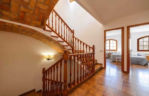 Eine Treppe mit Holzbalustern, einer Ziegelwand und einem Zimmer mit Bett und Schreibtisch.