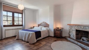 Ein Schlafzimmer mit Bett, Nachttischen, einem Kamin und einem großen Fenster.