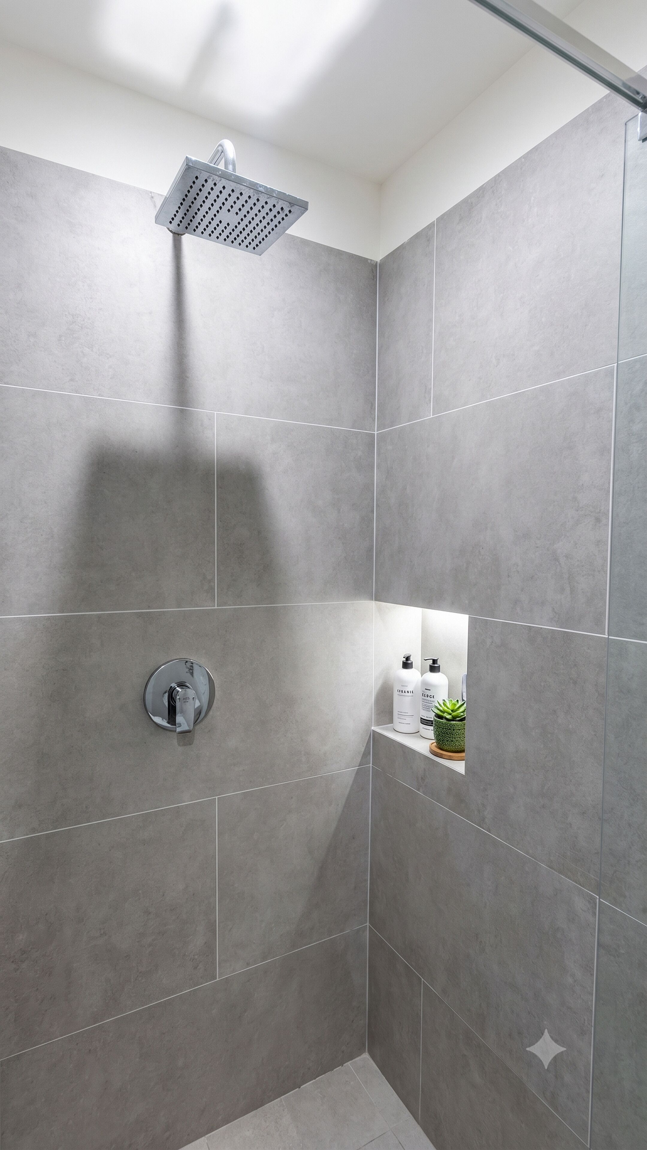 Eine Dusche mit Regendusche, Wandarmatur und Ablage für Toilettenartikel.