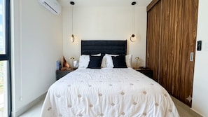A bedroom with a bed, bedside tables, a wooden wardrobe, and a window. - LUX 2-Storie 3-BDR 3.5 Bath Penthouse (Puerto Vallarta)