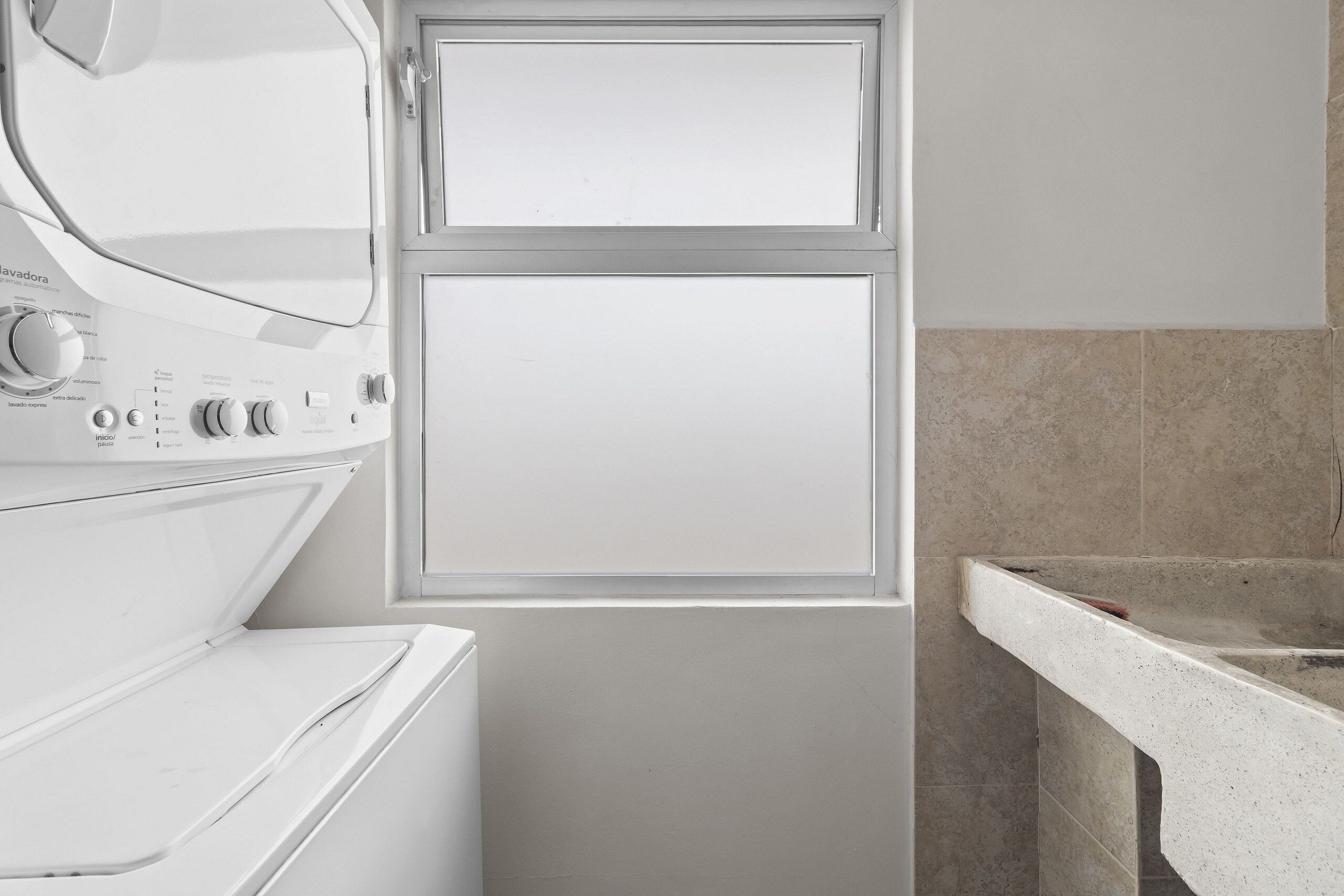 A laundry area with a washing machine, dryer, and a window.