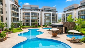 A modern hotel with a pool area, multiple balconies, and lush landscaping.