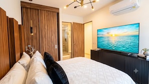 A bedroom with a bed, a TV, and a wooden wardrobe.