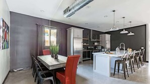 Une cuisine moderne avec un îlot central, un coin repas avec des chaises rouges et une grande fenêtre avec des rideaux.