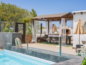 Ein Pool mit Pergola und Sitzbereich im Freien.