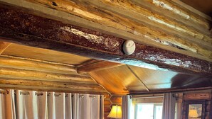 En stuga med träpanel på insidan, inredd med en röd soffa, en blå pall och en mönstrad matta.