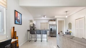 Una cocina moderna con refrigerador, microondas y taburetes de bar.