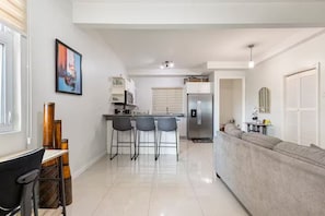 Eine moderne Küche mit Kühlschrank, Mikrowelle und Barhocker.