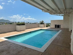 Ein Pool auf dem Dach mit freiem Blick auf die Stadt und Berge im Hintergrund.
