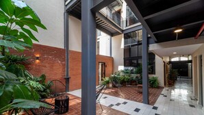 Um pátio espaçoso com muro de tijolos, plantas em vasos e área de estar externa.
