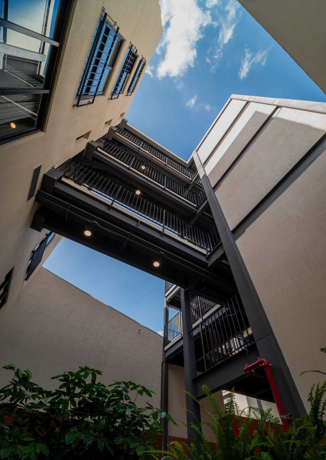 A multi-level outdoor structure with balconies, surrounded by vegetation.